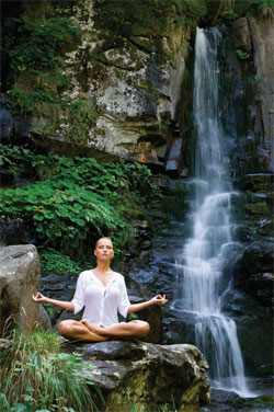woman meditating by a waterfall