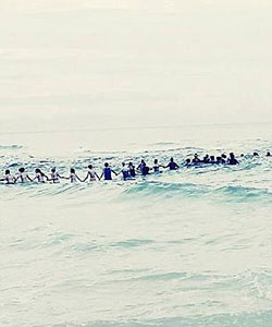 people in ocean forming a chain hand in hand