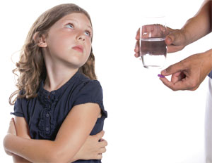 child being offered pill and glass of water