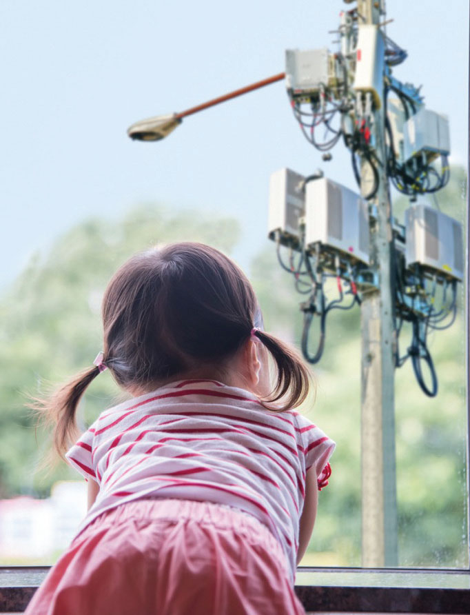 child looking out window at nearby cell tower