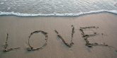 Love written in sand by the ocean